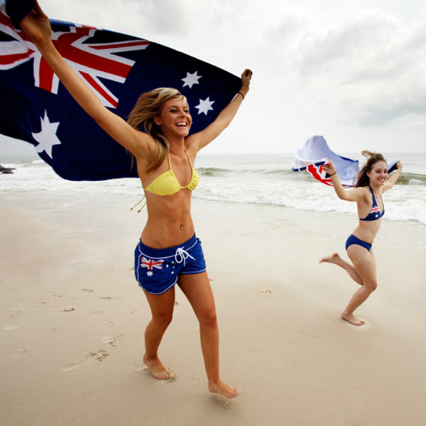 Girls running on beach with Australian flags