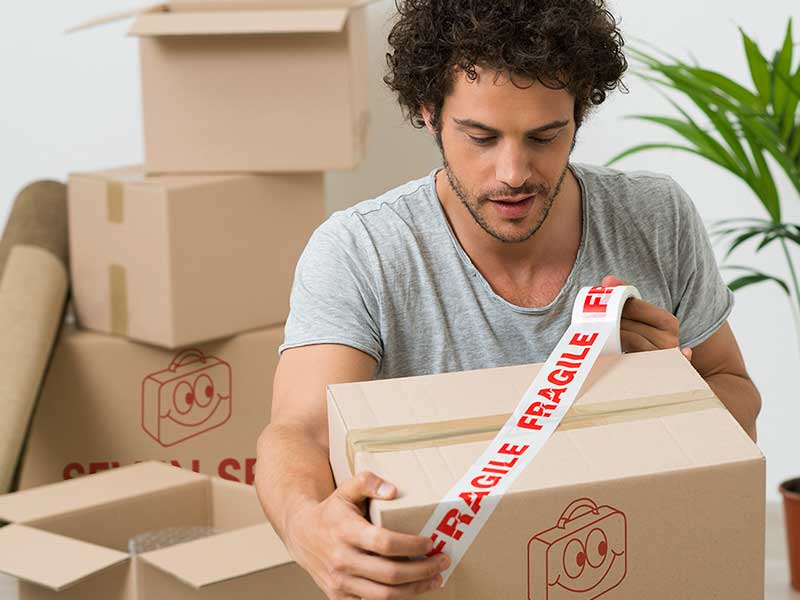 Young man taping boxes for shipping